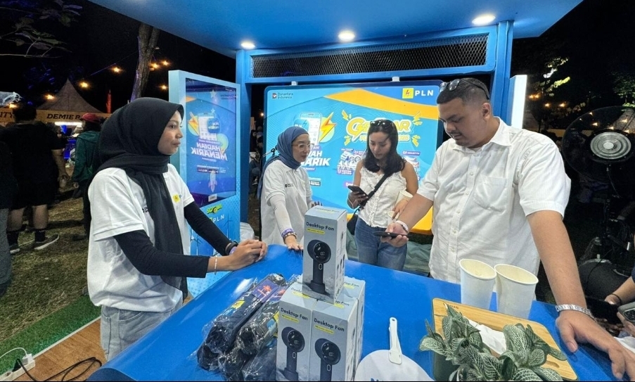 Petugas PLN dengan ramah memberikan penjelasan mengenai program Gelegar PLN Mobile dan hadiah menarik yang bisa diperoleh, menciptakan suasana booth yang hidup dan penuh interaksi.